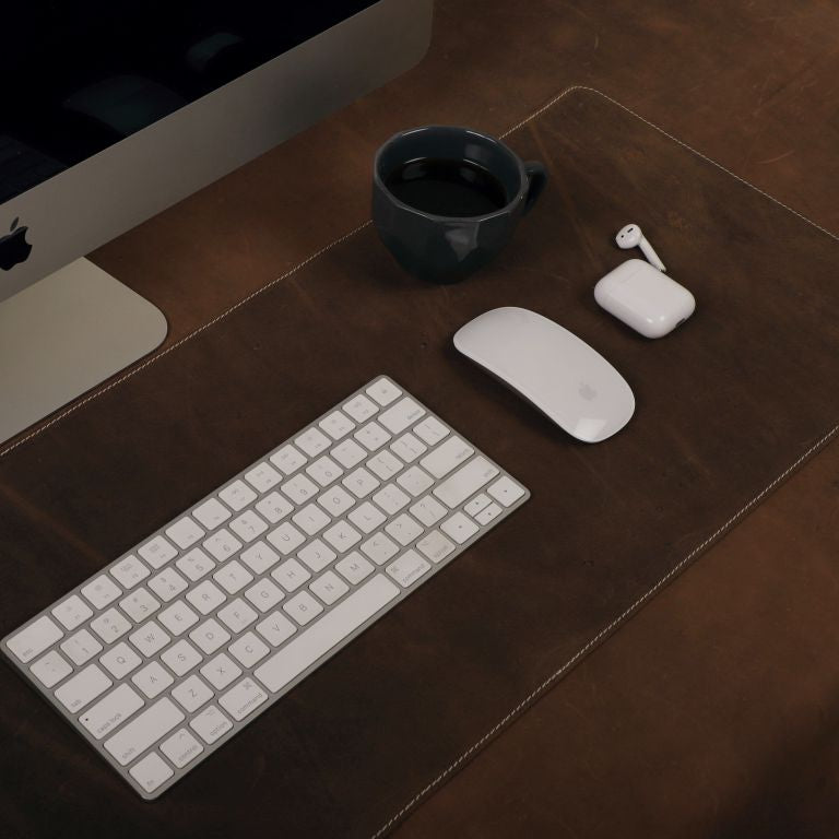 Computer setup with keyboard, mouse, and earbuds on a wooden desk