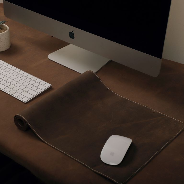 Computer setup with monitor, keyboard, mouse, and mouse pad on a wooden desk.