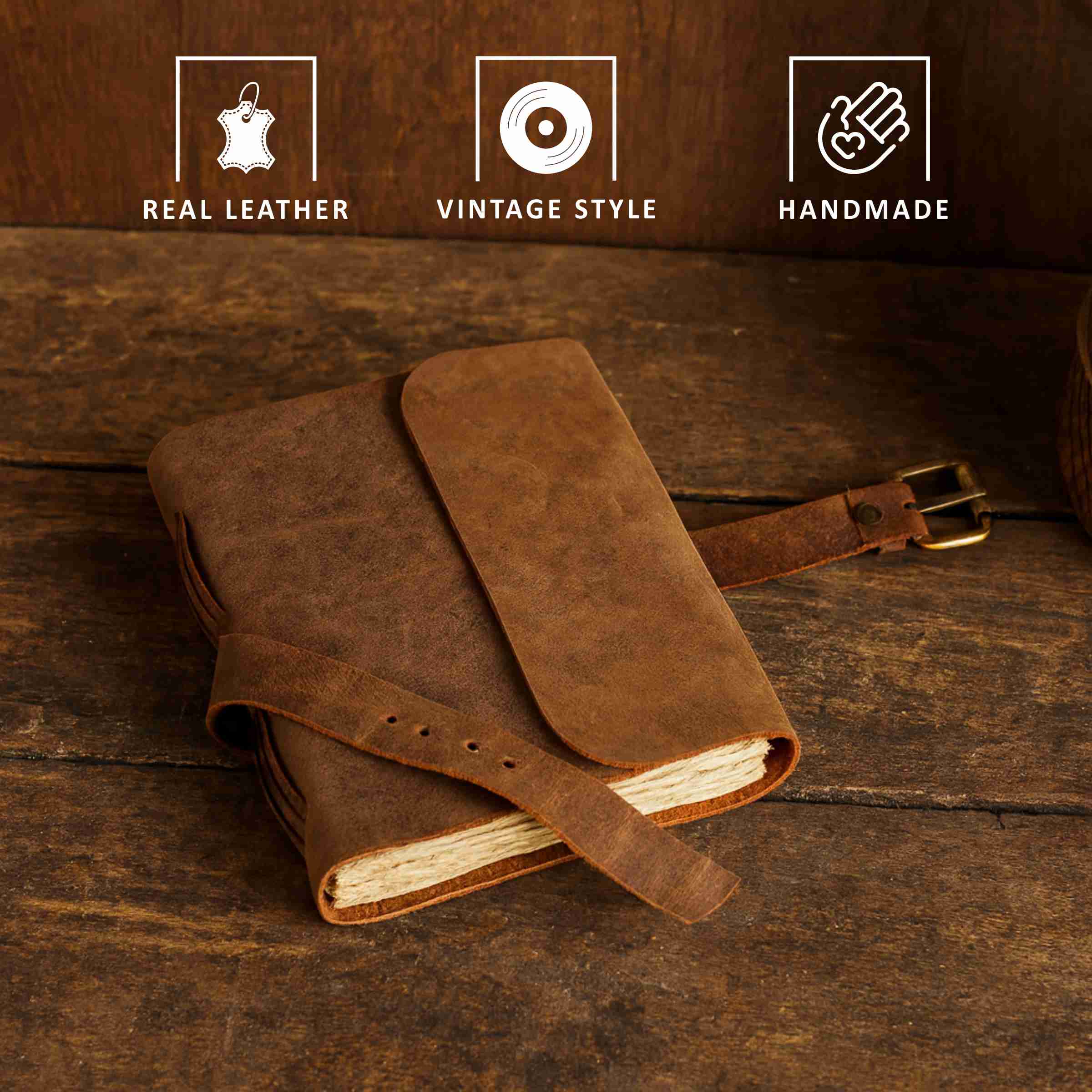 Brown leather notebook with strap on a wooden surface, featuring 'Real Leather', 'Vintage Style', and 'Handmade' icons.