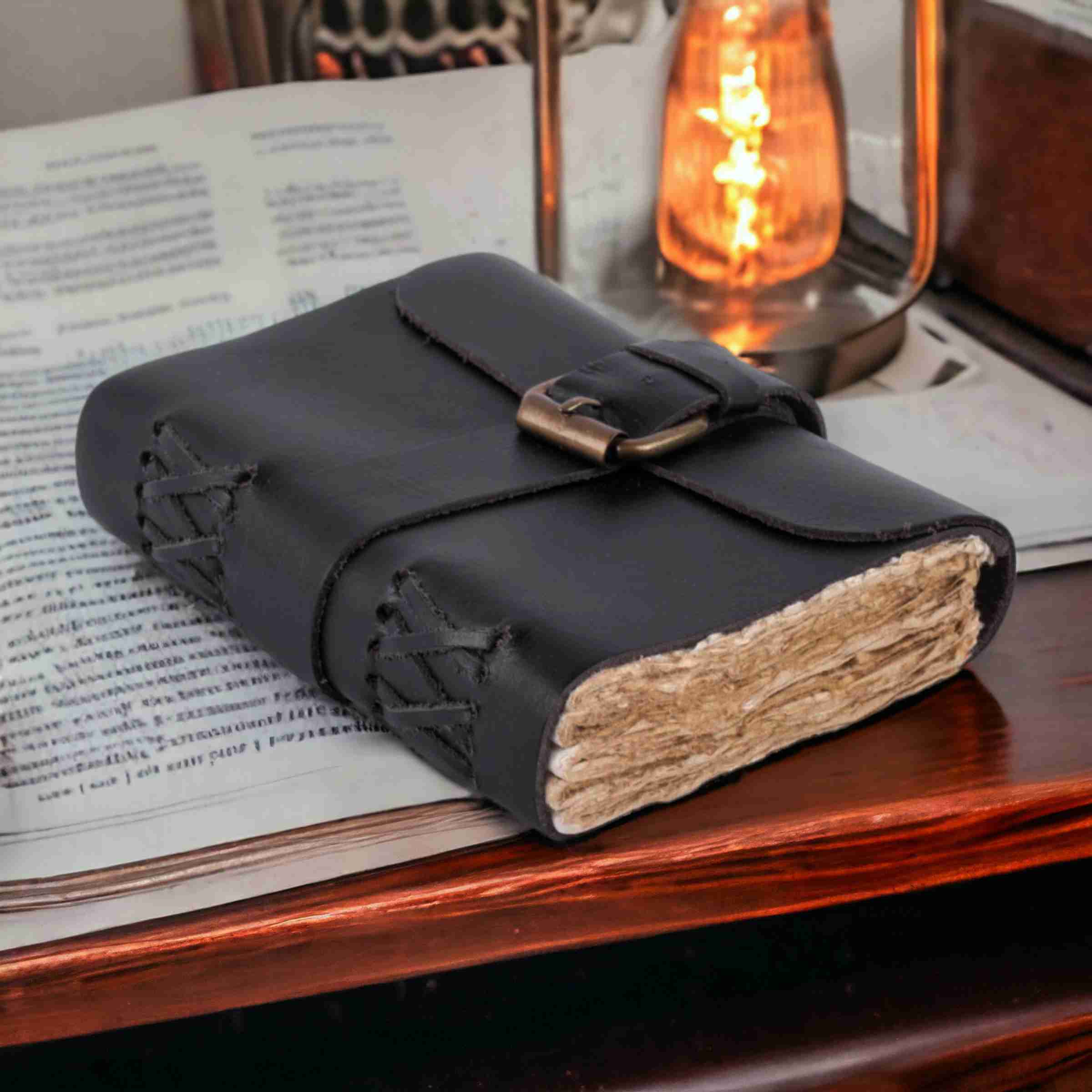 Black leather-bound notebook on an open book with a warm light in the background
