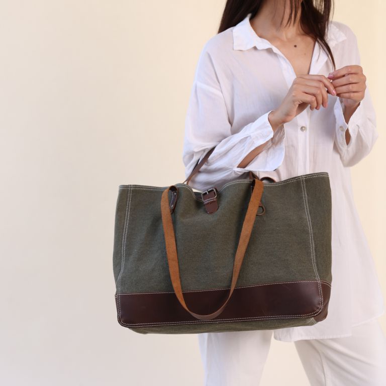 Person holding a green tote bag with brown accents against a plain background