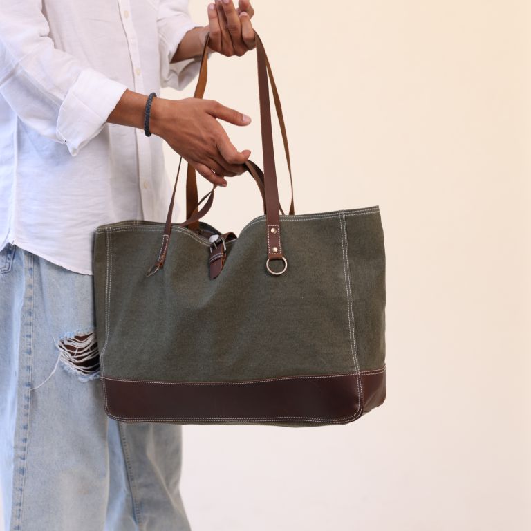 Person holding a green tote bag with brown accents against a plain background