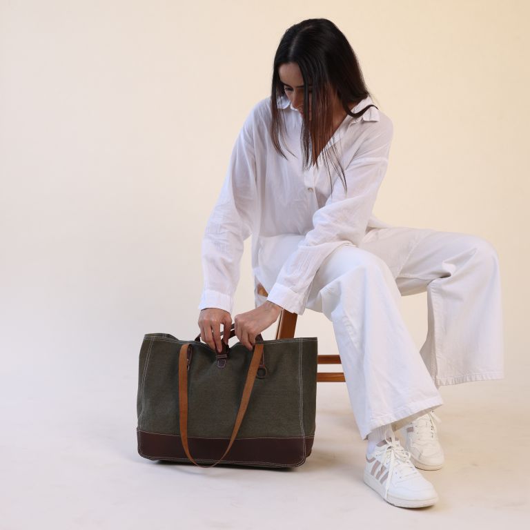 Woman sitting on a chair with a green bag on a white background