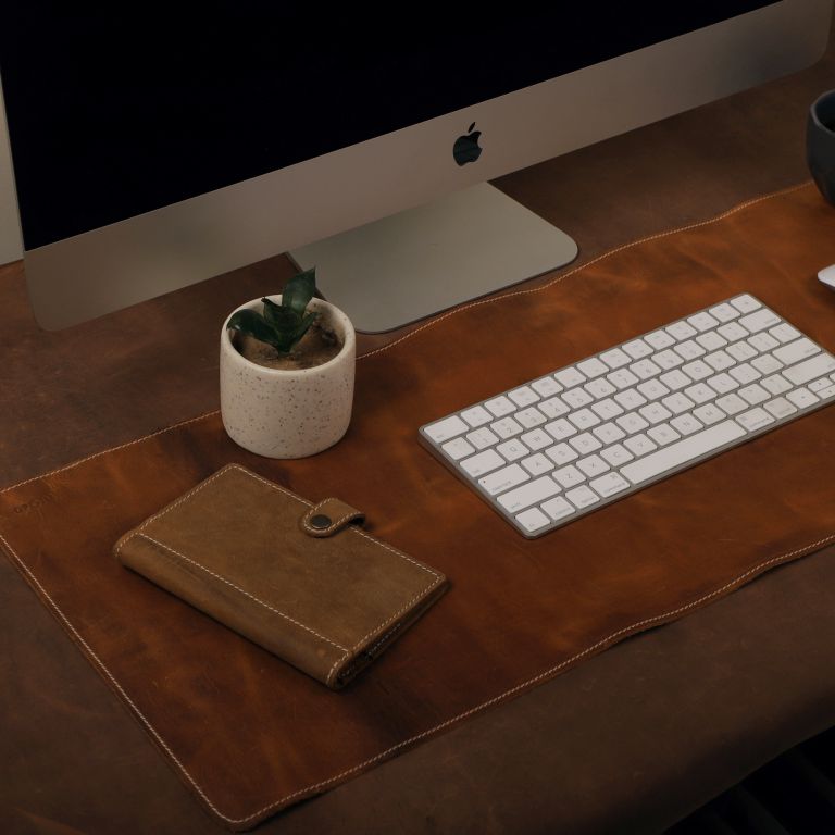 Wooden desk with computer monitor, keyboard, and small plant