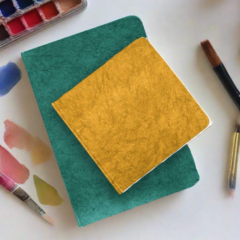 Two colorful watercolor blocks with painting tools on a white surface