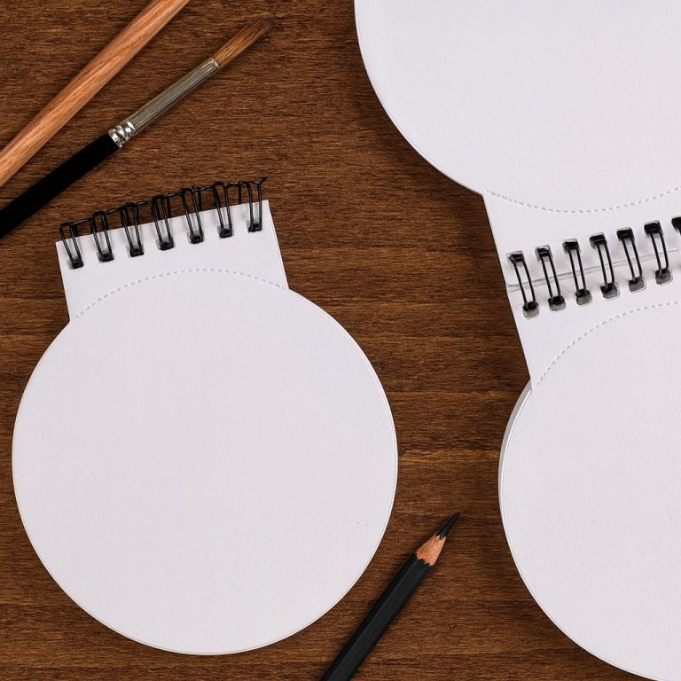 White round notebooks with black spiral bindings on a wooden surface.