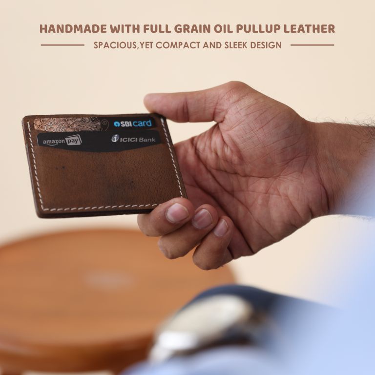 Hand holding a brown leather wallet with embedded cards on a blurred background