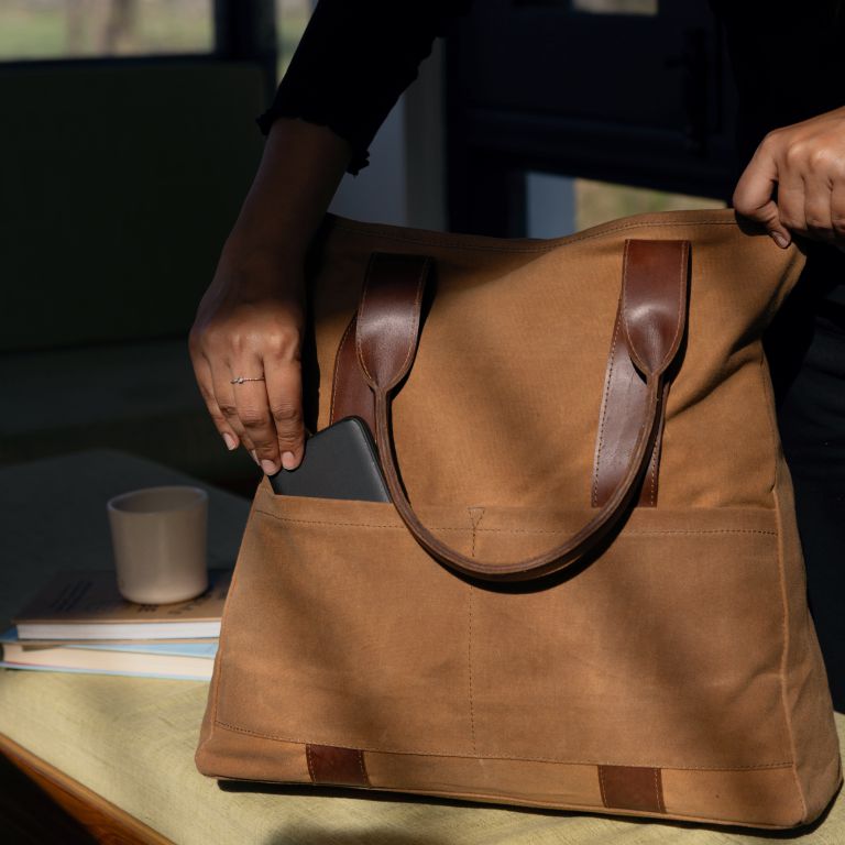 Brown leather bag held by a person with a blurred background