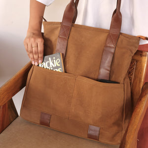 Brown tote bag with leather handles, showing its front pockets and minimalist design